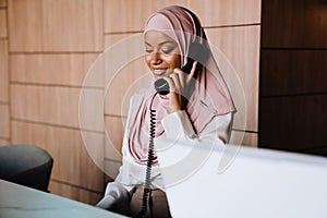 Muslim happy businesswoman talking on phone while working at reception