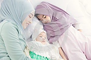 Muslim Hijab mother keep looking and cuddling sleeping baby with love and care on the bed