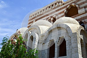 Muslim Islamic Arab mosque made of white brick for praying architecture with arches, domes and carved triangular windows against t