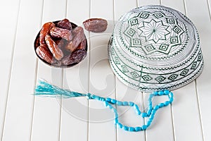 Muslim islamic concept taqiyah skullcap, blue rosary and dates medjul in coconut shel bowl.