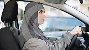 Muslim lady sitting in car looking rear view mirror, driving license, transport