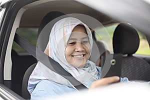 Muslim Lady Smiling When Looking at Her Phone in The Car