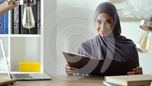 Muslim lady working in the office. Woman reading documents