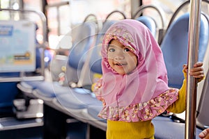 muslim little girl with hijab riding bus