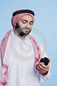 Muslim man checking supplement bottle