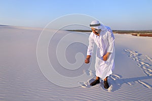 Muslim man develops sand along wind standing in middle of desert