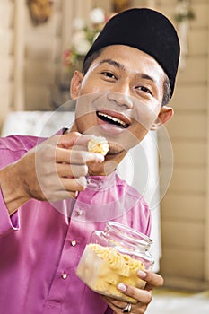 Muslim man eating traditional Malay cookie
