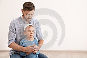 Muslim man and his son praying together indoors