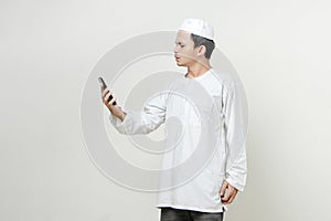 muslim man holding mobile phone and give stressful frustated expression. People religious Islam lifestyle concept. celebration