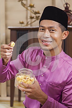 Muslim man holding traditional Malay cookie