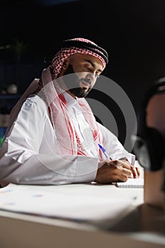 Muslim man jotting down on his notebook photo