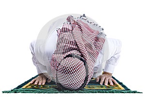 Muslim man with keffiyeh with agal in praying position salat on the prayer rug