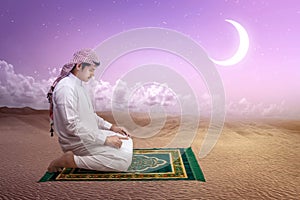 Muslim man with keffiyeh with agal in praying position salat on the prayer rug