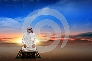 Muslim man with keffiyeh with agal in praying position salat on the prayer rug photo