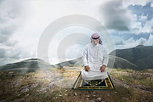 Muslim man with keffiyeh with agal in praying position salat on the prayer rug photo