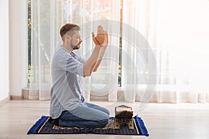 Muslim man with Koran praying on rug