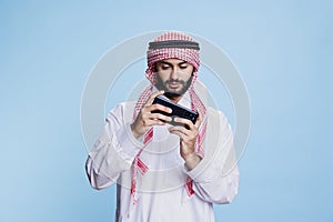 Muslim man playing online game on phone