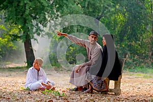 Muslim man point to some direction and explain to his wife and his son also look at the direction