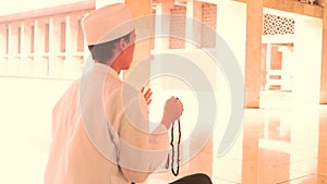 Muslim man praying with beads in mosque