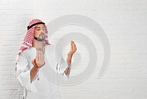 Muslim man praying near brick wal