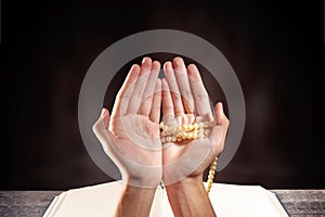 Muslim man praying with prayer beads on his hands in front of the opened quran