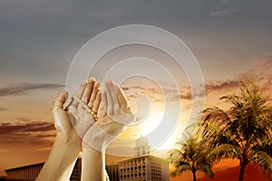 Muslim man praying with prayer beads on his hands and mosque with palm trees