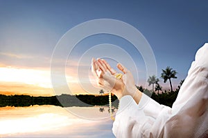 Muslim man praying with prayer beads on his hands at outdoor