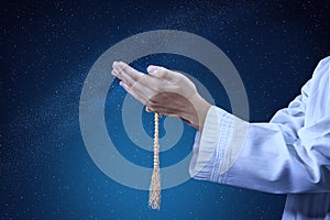 Muslim man praying with prayer beads on his hands at outdoor