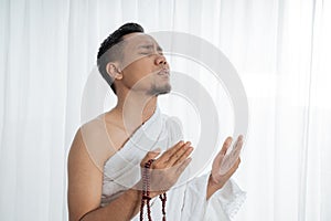 Muslim man praying in white traditional clothes