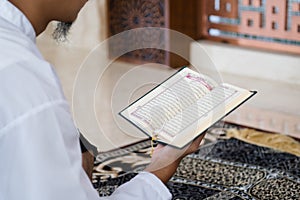 Muslim man reading holy Quran. Holy Quran in Hand with arabic text meaning of Al Quran. Islamic concept background