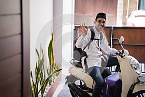 Muslim man ride motorcycle for idul fitri balik kampung mudik carrying suitcase