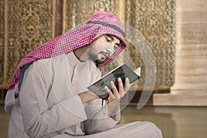 Hombre se sienta en mezquita a el lee Corán 