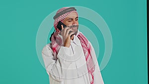 Muslim man in traditional attire texting