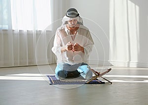 Muslim man in traditional clothes praying on rug