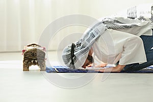 Muslim man in traditional clothes praying on rug