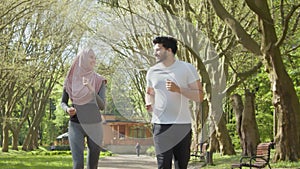 Muslim man and woman run. Happy arabian couple in activewear jogging at park. Healthy arabian couple enjoying morning