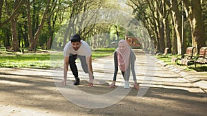 Muslim man and woman in starting position preparing for run. Muslim couple in sport clothes standing in start position