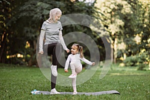 Muslim mother and her daughter, having workout in the park, doing high stepping exercise photo
