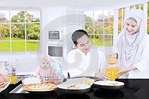 Muslim mother pouring orange juice