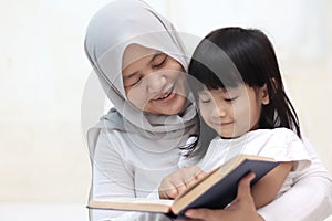 Muslim mother teach her daughter how to read the holy quran