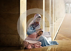 Muslim mother teach her daughter reading koran