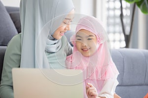 Muslim Mother working with laptop and Cute little baby playing toys in living room at home