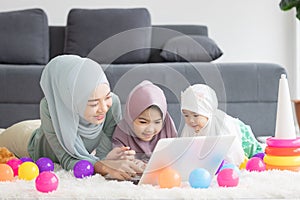 Muslim Mother working with laptop and Cute little baby playing toys in living room at home