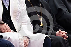 A Muslim mullah in white clothes and a Christian priest in a black cassock are sitting next to each other. The concept of photo