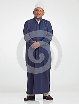 Muslim old man, studio portrait and islamic culture standing isolated on white background with arabic clothes. Senior