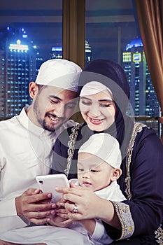 Muslim parents and their son using a cellphone