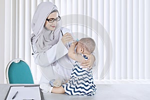 Muslim pediatrician checking her patient in the clinic