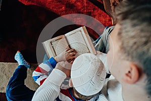 Muslim prayer father and son in mosque praying and reading holly book Quran together Islamic education concept
