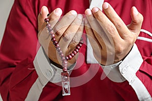 Muslim praying holding prayer beads  on white