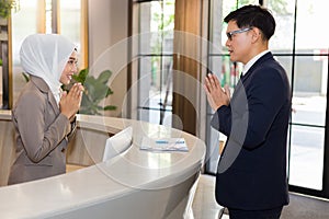 A Muslim receptionist introduces a polite greeting to the hotel guests